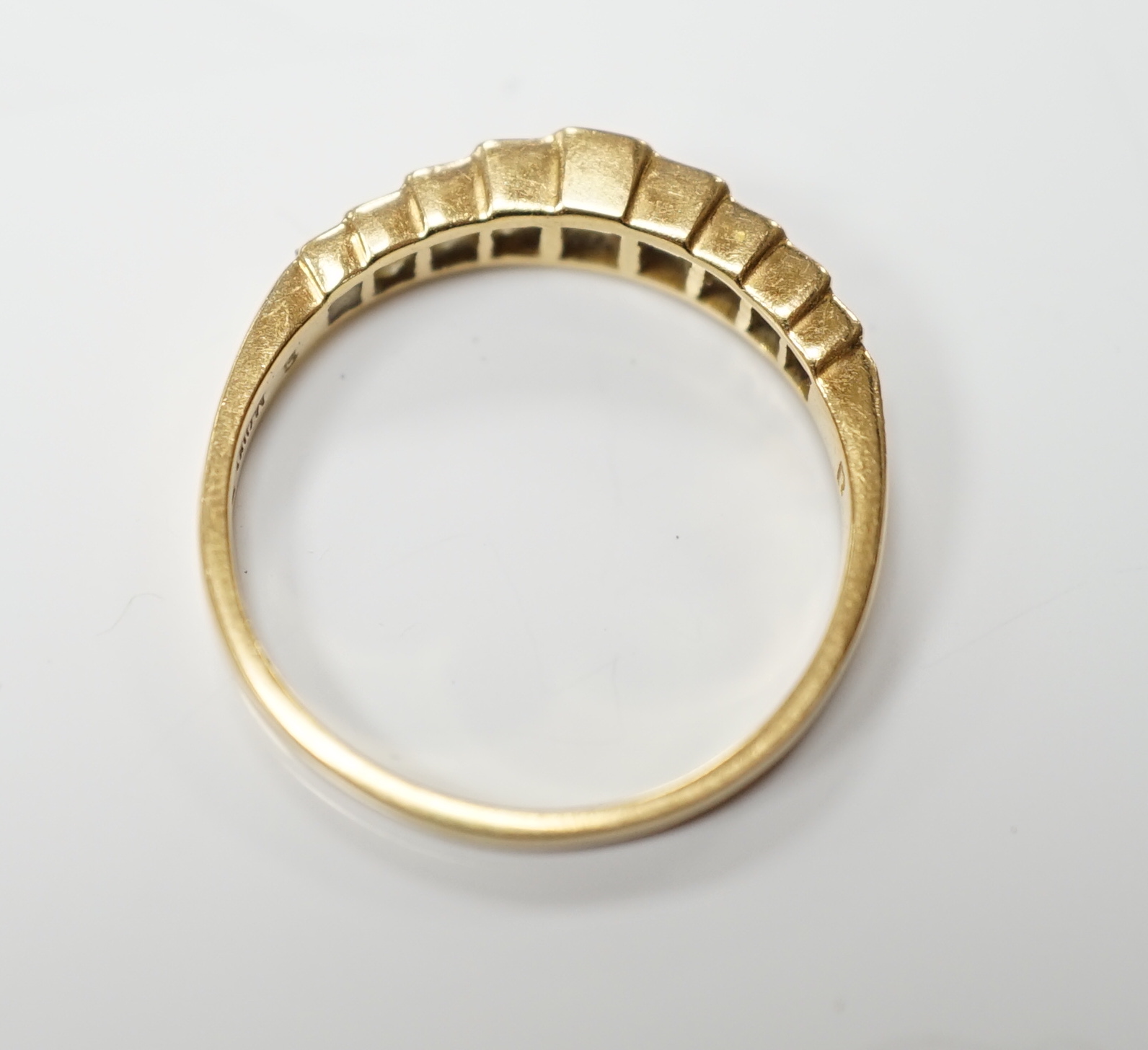 A modern 18ct gold and graduated nine stone princess cut diamond set half hoop ring, size L, gross weight 1.9 grams.